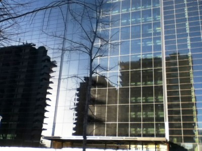 Stare, niewykończone budynki odbijające się w nowoczesnych szklanych biurowcach